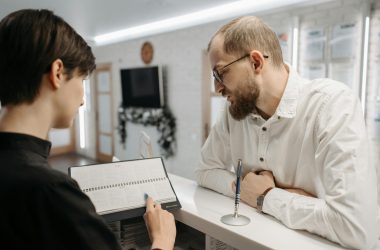 pexels photo 6809657 6809657 A receptionist and client converse over an appointment book at a clinic reception desk.